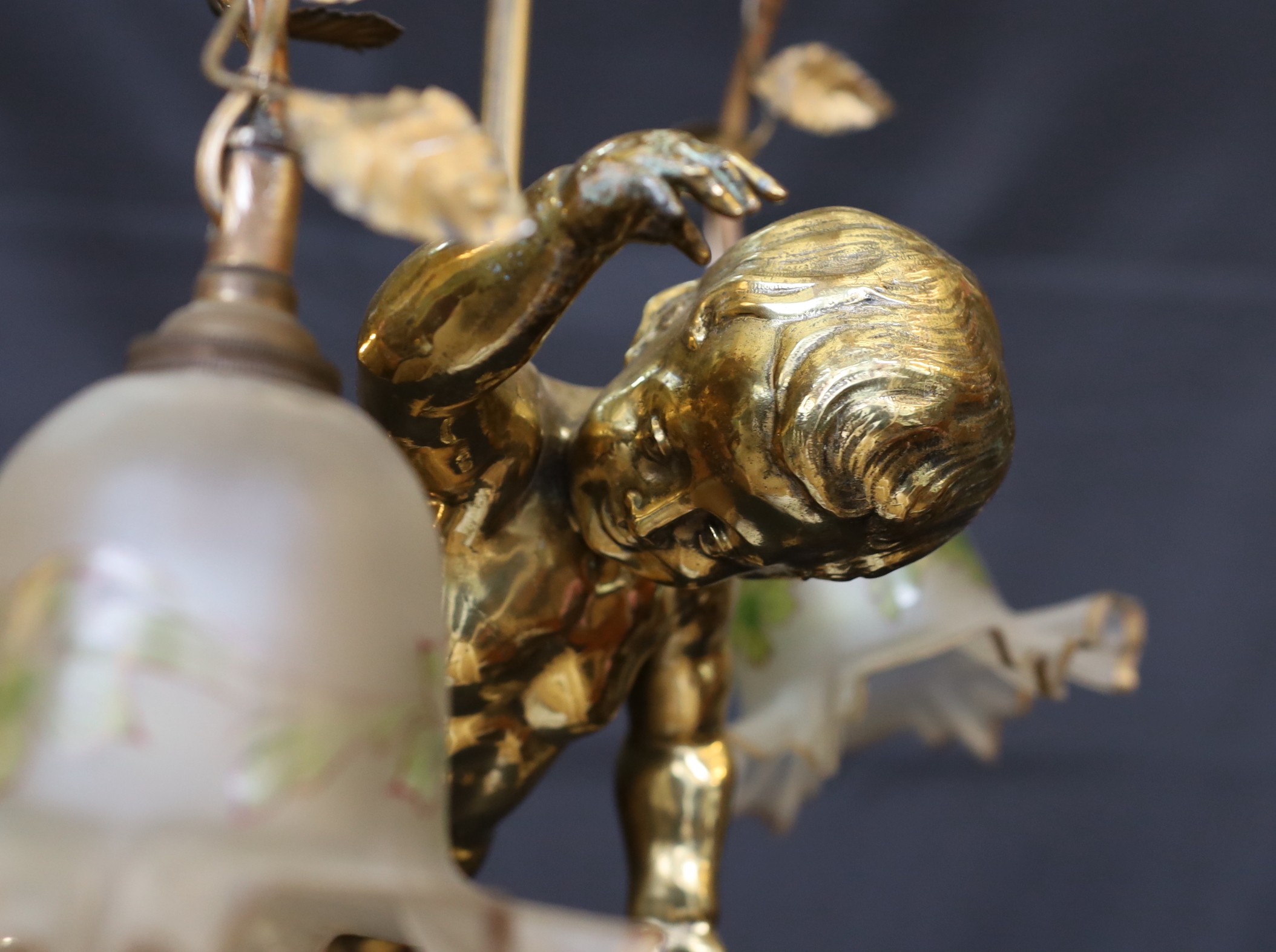 A 1920s French gilt bronze and wrought iron ceiling light with putto and rose motifs, drop 71cm. width 44cm